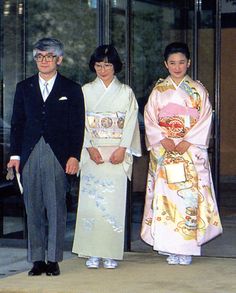 two men and one woman standing in front of a building with glass doors, dressed in traditional japanese clothing