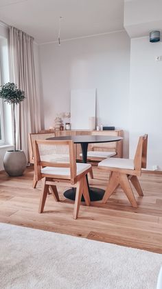 a table and chairs in a room with wood floors, white rugs and large windows