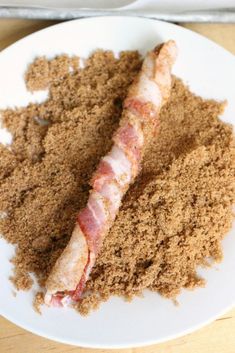 a white plate topped with meat and seasoning on top of a wooden table next to a fork