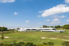 an aerial view of a golf course with white buildings in the background and green grass