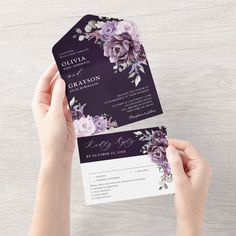 two hands holding up a purple and white floral wedding program card with matching envelopes