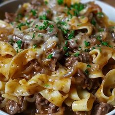 a bowl filled with pasta and meat covered in sauce