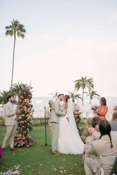 a bride and groom standing at the end of their wedding ceremony in front of an ocean view