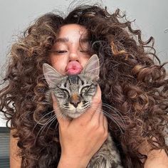 a woman holding a cat with her tongue sticking out