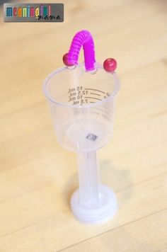 a plastic cup with a pink handle on top of a wooden table