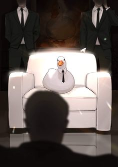 two men in suits stand behind a white couch with a duck on it's back