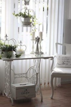 a white table with some plants on it and two chairs in front of the window