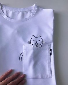 a woman's hand holding onto a white t - shirt with a cat drawn on it