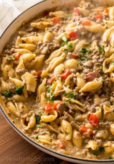 a pot filled with pasta and meat in a white sauce on top of a wooden table