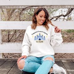 a woman sitting on a bench wearing a white sweatshirt with the words disneyland world on it