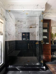 a bathroom with black and white marble walls, flooring and a walk in shower