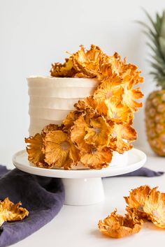 there is a white cake with yellow flowers on the top and pineapples around it