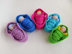 four crocheted baby booties sitting on top of a white table next to each other