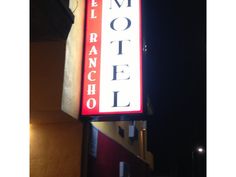 a hotel sign hanging off the side of a building in front of a dark sky