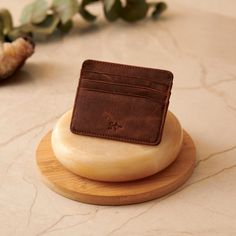 a brown leather wallet sitting on top of a wooden coaster