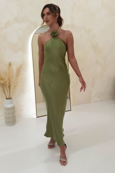 a woman standing in front of a mirror wearing a green dress