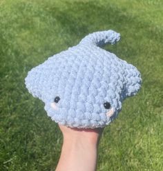 a hand holding up a crocheted blue animal