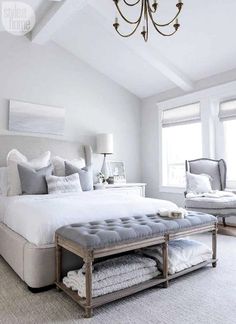 a bedroom with a bed, chandelier and two windows in the ceiling area