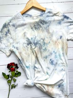 a tie dye t - shirt next to a single rose