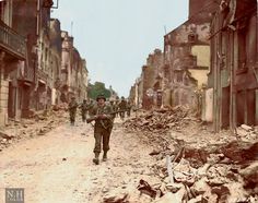 an old photo of soldiers walking down a street in the middle of destroyed buildings and rubble