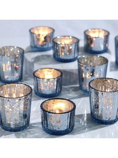 blue glass tealight candles are arranged in a circle on a white tablecloth with gold flecks