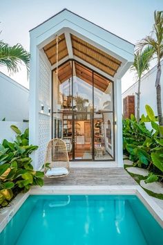 a pool with a chair next to it in front of a white building and palm trees