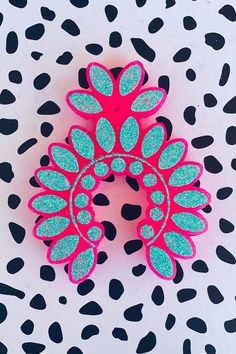 a pair of pink and blue hair clips on a spotted surface with black dots,