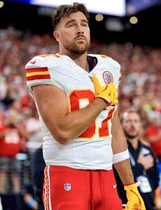 a football player standing on the sidelines with his hands in his pockets and wearing yellow gloves