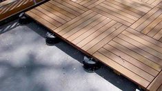 a wooden bench sitting on top of a cement ground next to a metal rail and tree