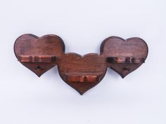 two wooden heart shaped hooks on a white wall