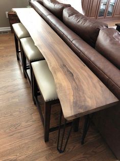 a couch and some stools in a living room next to a table with chairs on it