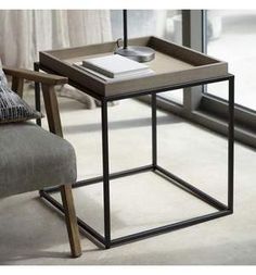 a table with a book on it next to a chair and window in the background