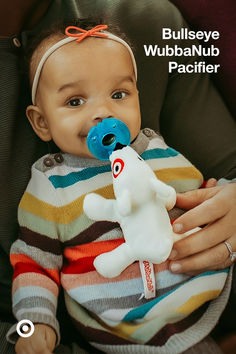 a woman holding a baby with a stuffed animal in it's mouth