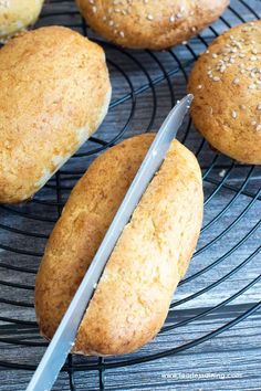 several loaves of bread sitting on a wire rack with a knife in the middle