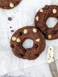 three chocolate cookies with white chocolate chips on top and one has a bite taken out of it