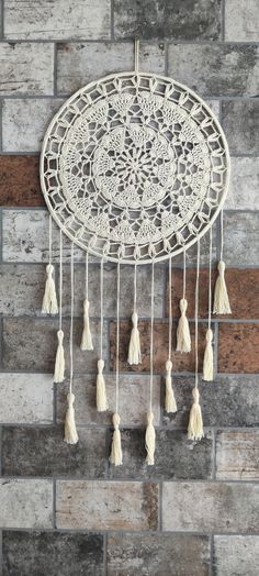 a white dream catcher hanging on a brick wall