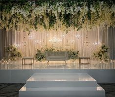 an elegant wedding setup with white flowers and greenery on the wall, set up for a ceremony