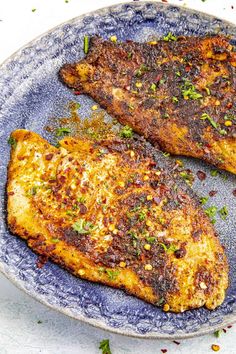 two pieces of chicken on a plate with spices and seasoning sprinkles