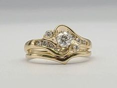 two gold wedding rings with diamonds on each one and an engagement ring in the middle