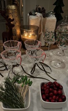 the table is set with wine glasses, candy canes and cranberries