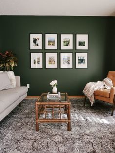 a living room with green walls and pictures on the wall above the couch, coffee table