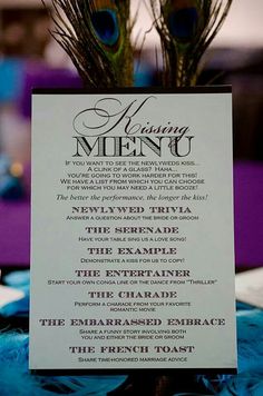 a menu card with peacock feathers sitting on it's table cloth at a wedding reception