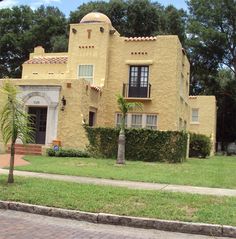 a yellow house with a palm tree in the front yard