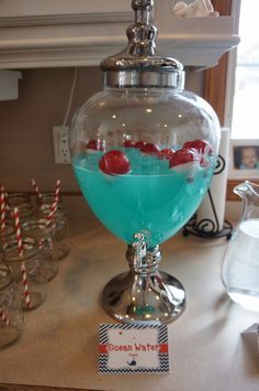 a blue liquid in a glass bowl with strawberries on the rim and candy sticks