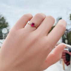 a woman's hand with a ring on it that has a pink stone in the middle