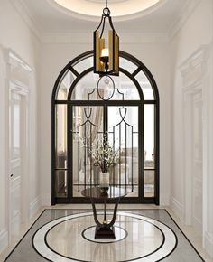 a foyer with an arched glass door and chandelier