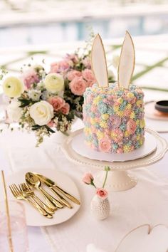 there is a cake decorated with flowers and bunny ears on the plate next to it