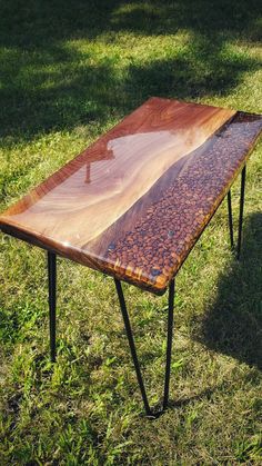 a table made out of wood and metal legs in the middle of some green grass