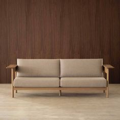 a couch sitting in front of a wooden wall with a brown paneled wall behind it