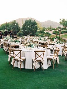 the tables are set up with white linens and wooden chairs for an outdoor wedding reception